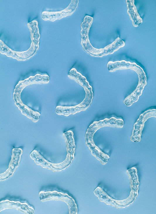 Flat lay of several clear Brux night guards from SayCheeseClub, designed to protect teeth from grinding damage.