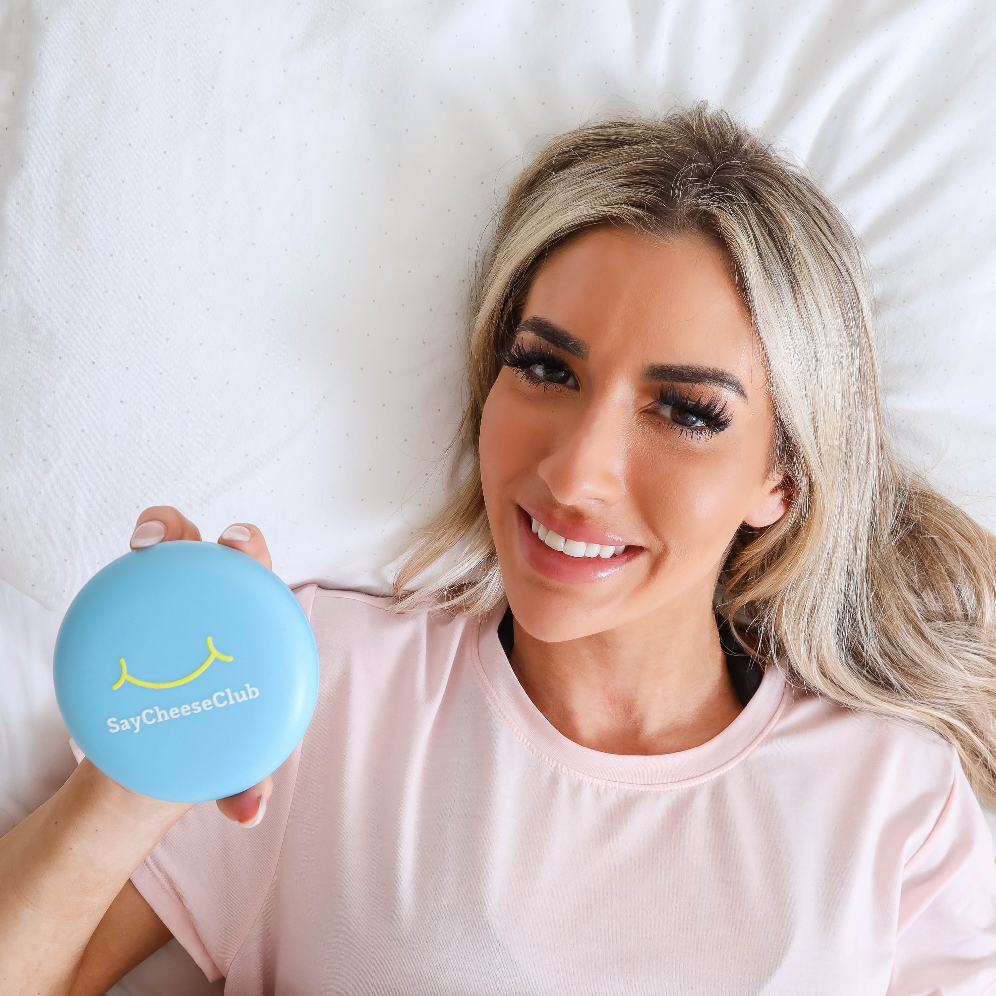Woman laying in bed holding sleep teeth guards